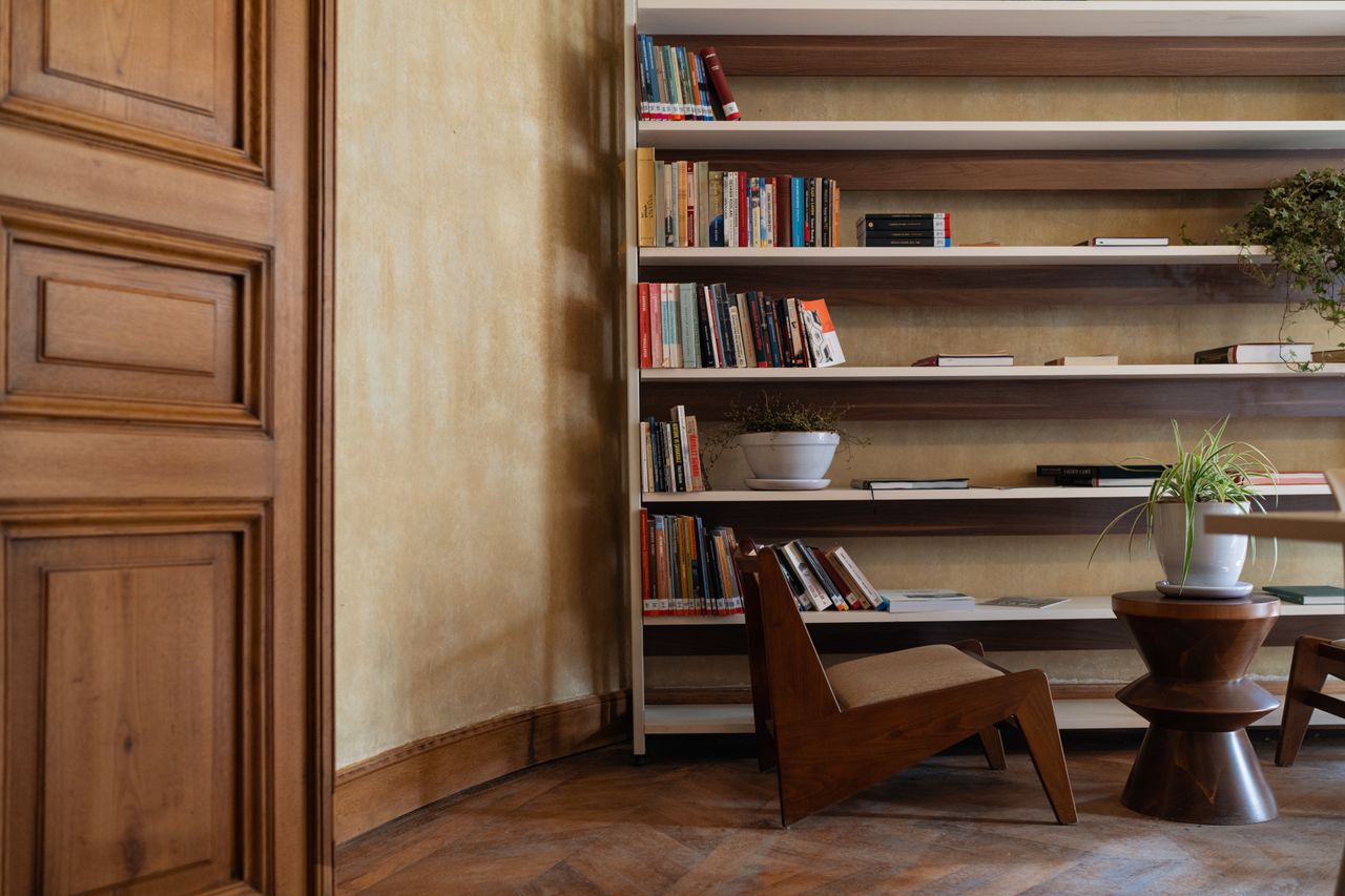 Warm and inviting reading corner with bookshelves, wooden chair, and plant decor.