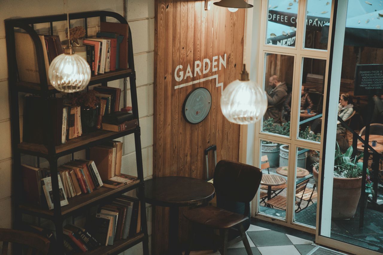 Charming indoor café corner with bookshelves, vintage lamps, and a cozy ambiance.
